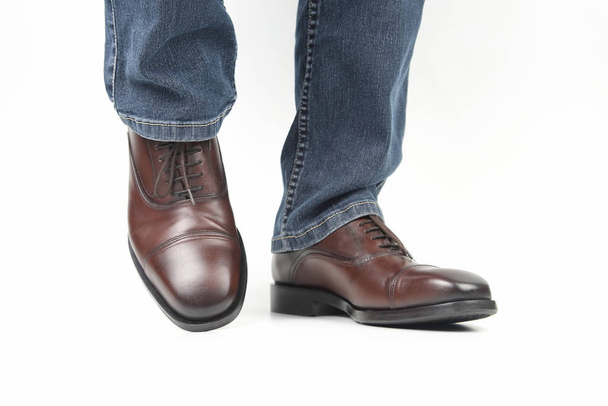 Male legs in jeans and brown classic shoes on white background - Photo, image