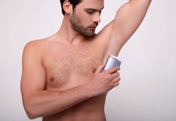 Close-up, a white male uses deodorant. - Фото, изображение