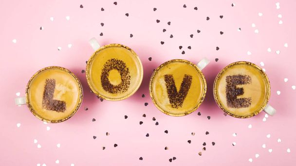 Slovo láska se skládá z písmen napsaných na pěně kávy na růžovém pozadí. Svatý Valentýn. - Fotografie, Obrázek
