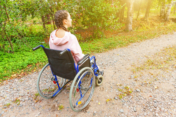 Giovane donna handicappata felice in sedia a rotelle su strada nel parco ospedaliero in attesa di servizi paziente. Ragazza paralizzata in sedia non valida per disabili all'aperto in natura. Concetto di risanamento. - Foto, immagini