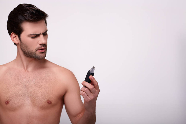 A brooding young guy shirtless with a trimmer in his hand. - Foto, Imagem