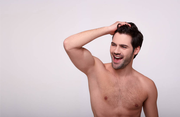 Enthusiastic guy looks away and holds his hand on his hair - Fotoğraf, Görsel