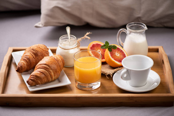Śniadanie kontynentalne. Taca śniadaniowa na łóżku z kawą, pomarańczowa - Zdjęcie, obraz