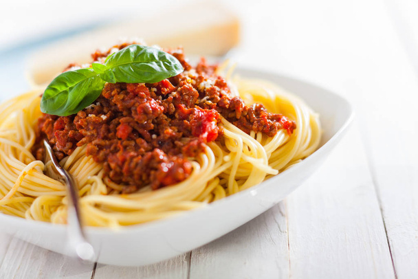 Dish of Italian spaghetti with rich tomato based Bolognaise sauce garnished with fresh basil leaves for a healthy Mediterranean diet - Fotografie, Obrázek