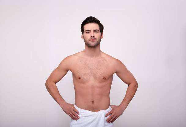Young caucasian sexy shirtless macho posing in towel isolated on grey - Foto, Imagem