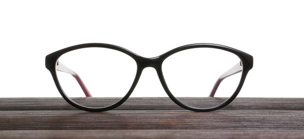 Stylowe okulary na drewnianym stole na białym tle - Zdjęcie, obraz