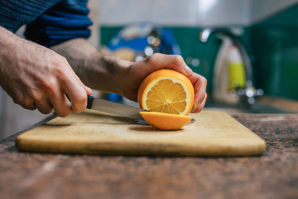 Close Up Of Man's Hands Cutting Orange - 写真・画像