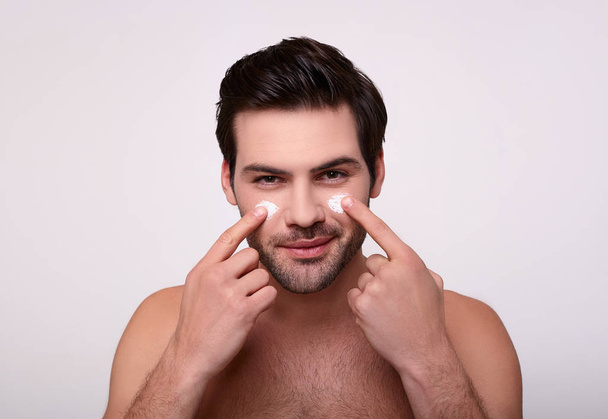 A young Caucasian man with moisturizer on his face. - Fotó, kép