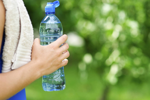 woman holding bottle of water on green grass - Fotografie, Obrázek