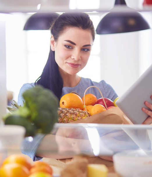 Smiling woman taking a fresh fruit out of the fridge, healthy food concept - Photo, Image