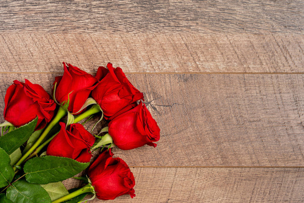 Red roses over wooden background top view - Fotografie, Obrázek