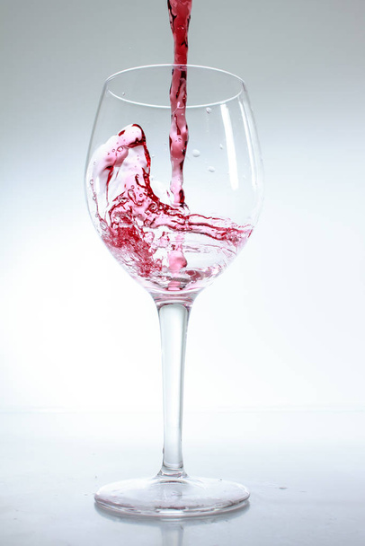 Red wine poured in a glass on white background - Photo, Image