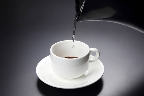 gotowaną wodę wlewa się do białego kubka z czarną kawą. gorąca d - Zdjęcie, obraz