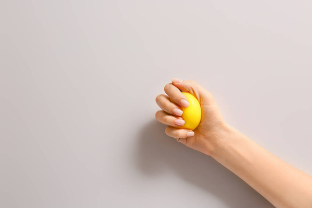Hand squeezing stress ball on light background - Фото, зображення