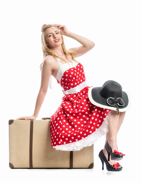 a woman in polka dot dress sitting on a suitcase and waiting - Foto, afbeelding