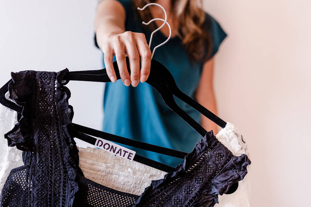 уборка концепции, женщина держит одежду вешалки с черным и
 - Фото, изображение