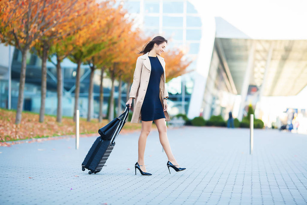 Mosolygó nő utas eljárás kilépés kapu húz bőrönj keresztül repülőtéren Concourse. - Fotó, kép