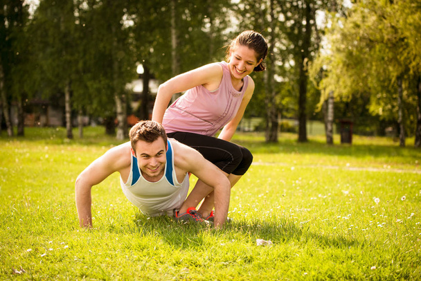 Sport man making push-ups while woman is sitting on him as a weight - Fotoğraf, Görsel