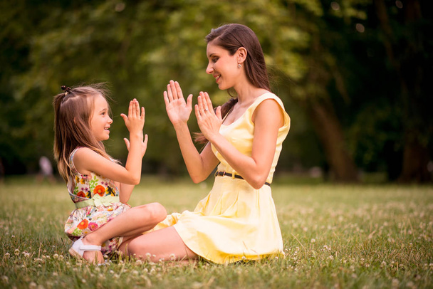 Clapping hands - mother playing with her daughter outdoor in nature - 写真・画像