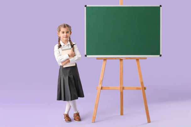 Μικρή μαθήτρια κοντά μαυροπίνακα στο φόντο χρώμα - Φωτογραφία, εικόνα