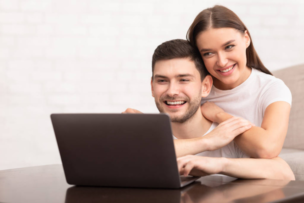 Guy pracuje na notebooku sedí s přítelkyní na gauči vnitřní - Fotografie, Obrázek