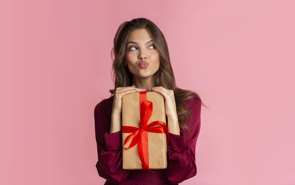 Portrait of funny girl with gift box over pink background - Zdjęcie, obraz