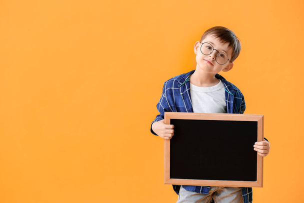 Little schoolboy with chalkboard on color background - Foto, afbeelding