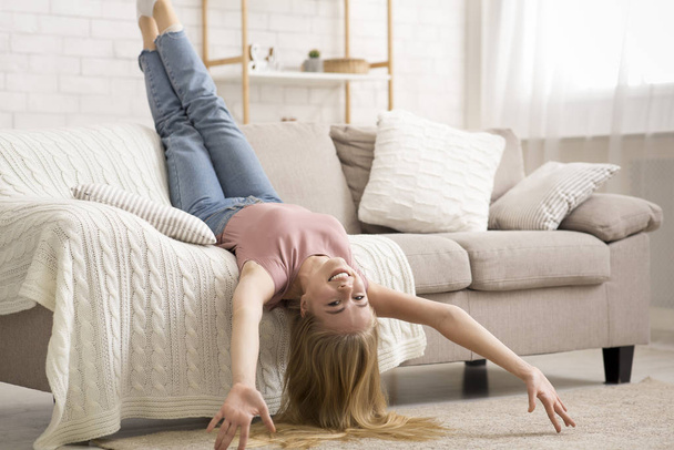 Young woman laying upside down on couch at home - Photo, Image