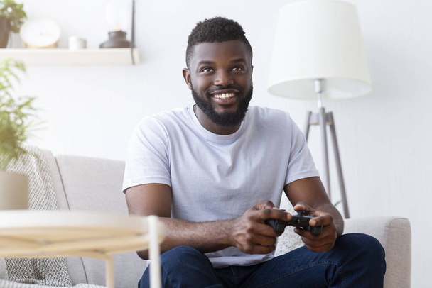 アフリカ系アメリカ人のゲーマーは自宅でゲームパッドで遊ぶ - 写真・画像