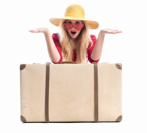 a woman sitting behind a suitcase and is amazed - Фото, зображення