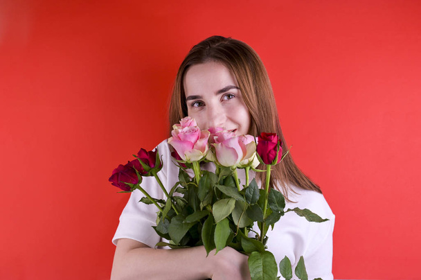 The concept of Valentines Day and Womens Day. Happy young girl holding a bouquet of roses.  - Photo, image