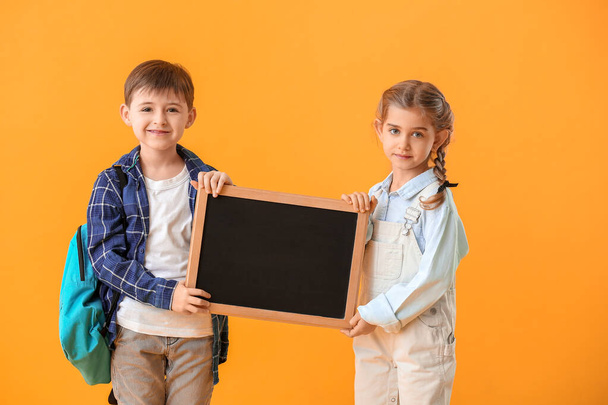 Little pupils with chalkboard on color background - Foto, afbeelding