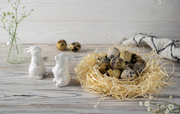 Festive happy easter decoration with quail eggs and ceramic bunnies - Фото, изображение