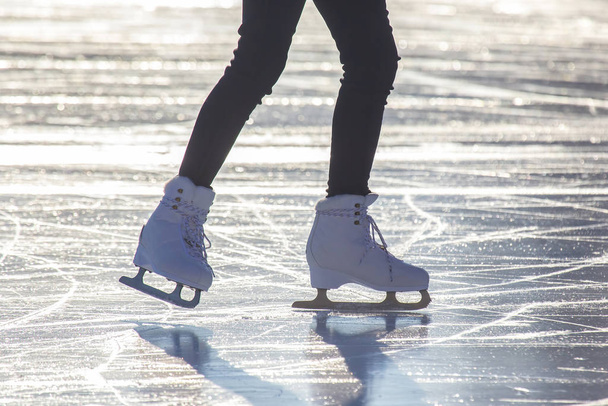 Naisten jalat valkoisissa luistimissa luistinradalla. Urheilu ja harrastukset. H
 - Valokuva, kuva