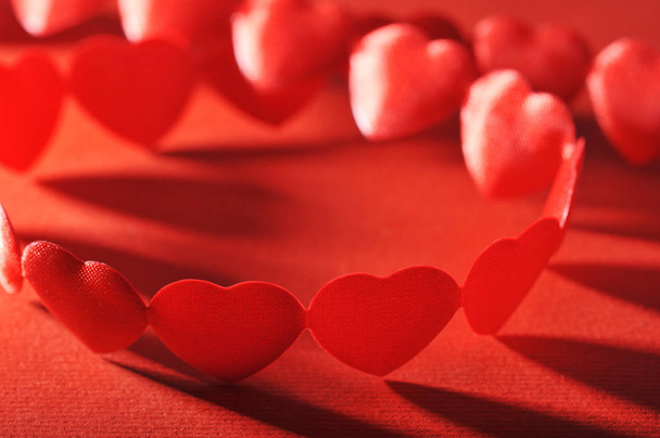 chain of small red fabric heart on a red background\n - Foto, Imagem