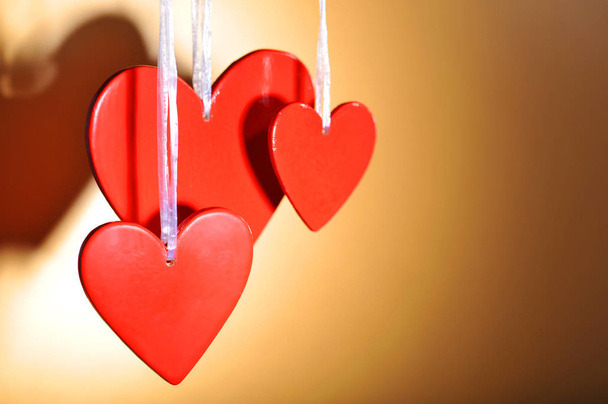three red wooden heart in front of golden background\n - Foto, Imagem
