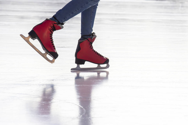 stopy w czerwonych łyżwach na lodowisku. Zainteresowania i sport. Urlop - Zdjęcie, obraz
