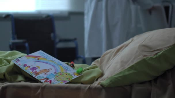 Zaměření na lůžko s kresbou dítěte, lékař chodit na pozadí - Záběry, video