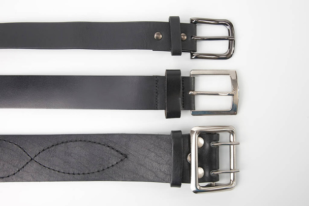tre cinture in pelle nera su sfondo bianco. articoli e vestiti
 - Foto, immagini