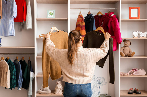 Woman choosing winter clothes near wardrobe - Foto, Imagen