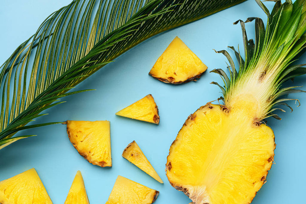 Свежий срезанный ананас и пальмовый лист на цветном фоне
 - Фото, изображение