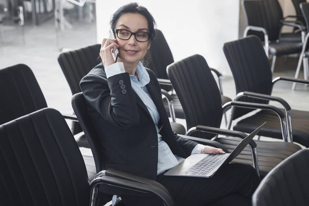 Un formateur d'entreprise confiant parle au téléphone dans une salle de conférence vide
 - Photo, image