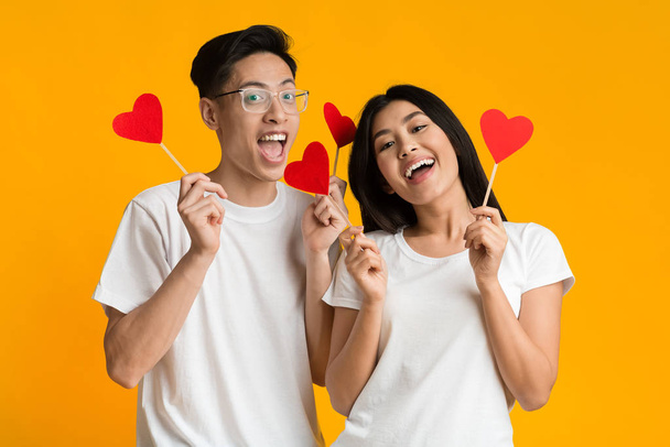 Счастливая азиатская пара с красными карточками в форме сердца
 - Фото, изображение