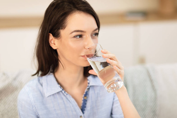 Улыбающаяся девушка пьет чистую воду из стекла
 - Фото, изображение