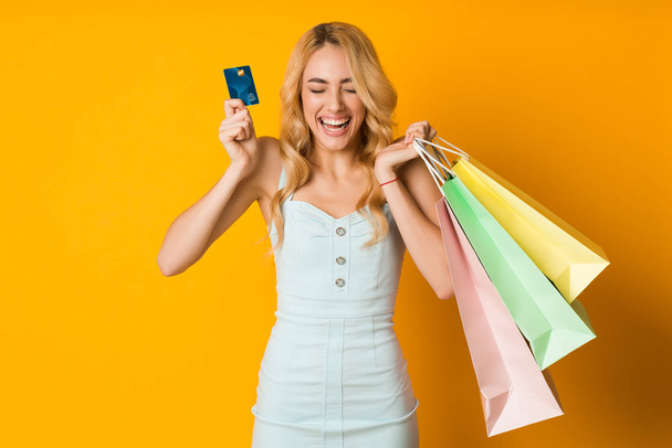 Shopping concept. Overjoyed woman holding credit card and paper bags - Фото, зображення