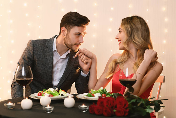 Bello uomo baciare mano della sua ragazza mentre pranzare in ristorante
 - Foto, immagini