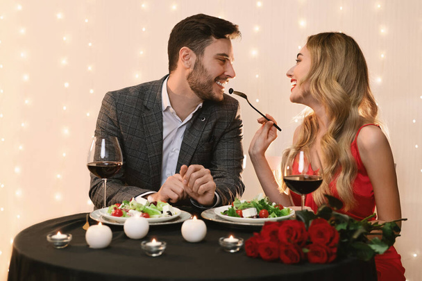 Φροντίδα γυναίκα σίτιση φίλο με σαλάτα σε ρομαντικό ραντεβού στο εστιατόριο - Φωτογραφία, εικόνα