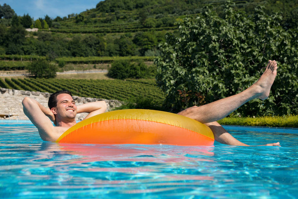 Man in pool with swimming tyres - Fotó, kép