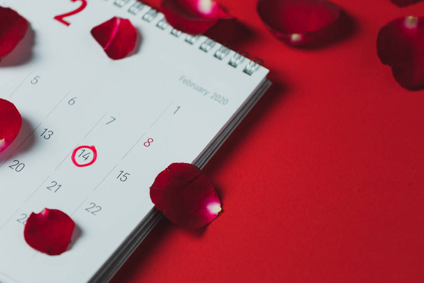 Kalendarz biały papier i płatki czerwonej róży umieszczone na czerwonym tle - Zdjęcie, obraz