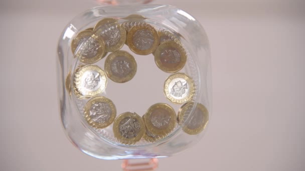 Červíčí pohled na někoho, kdo dává librové mince do skleněné sklenice - Záběry, video